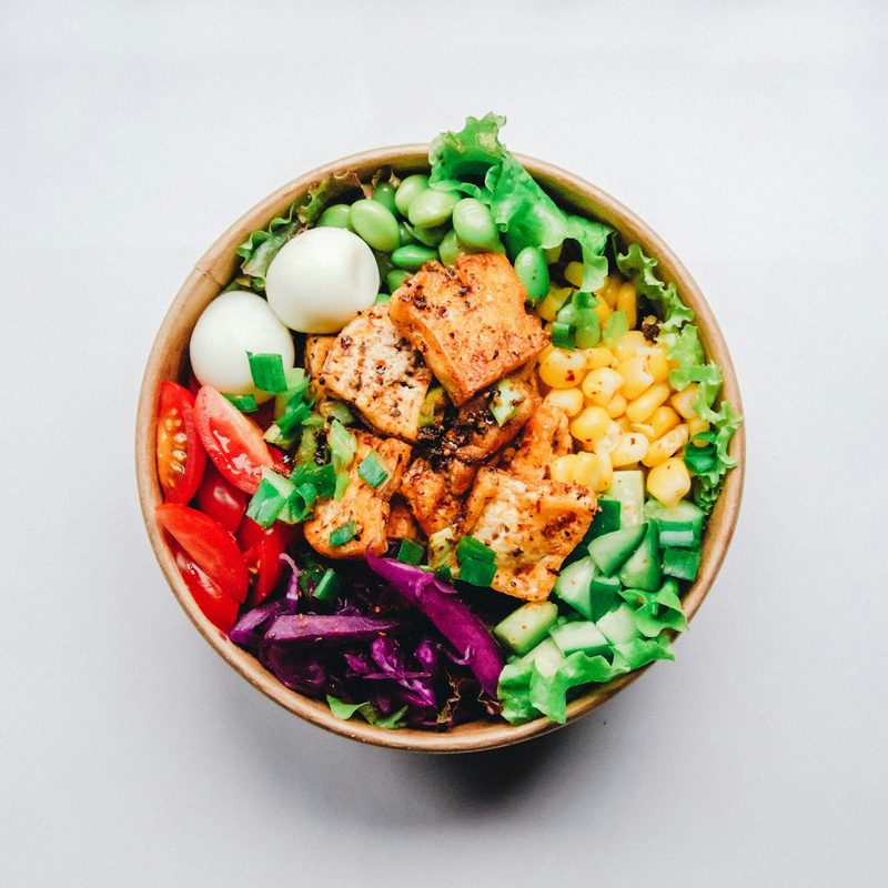 A grain bowl with salmon, edamame, corn and greens